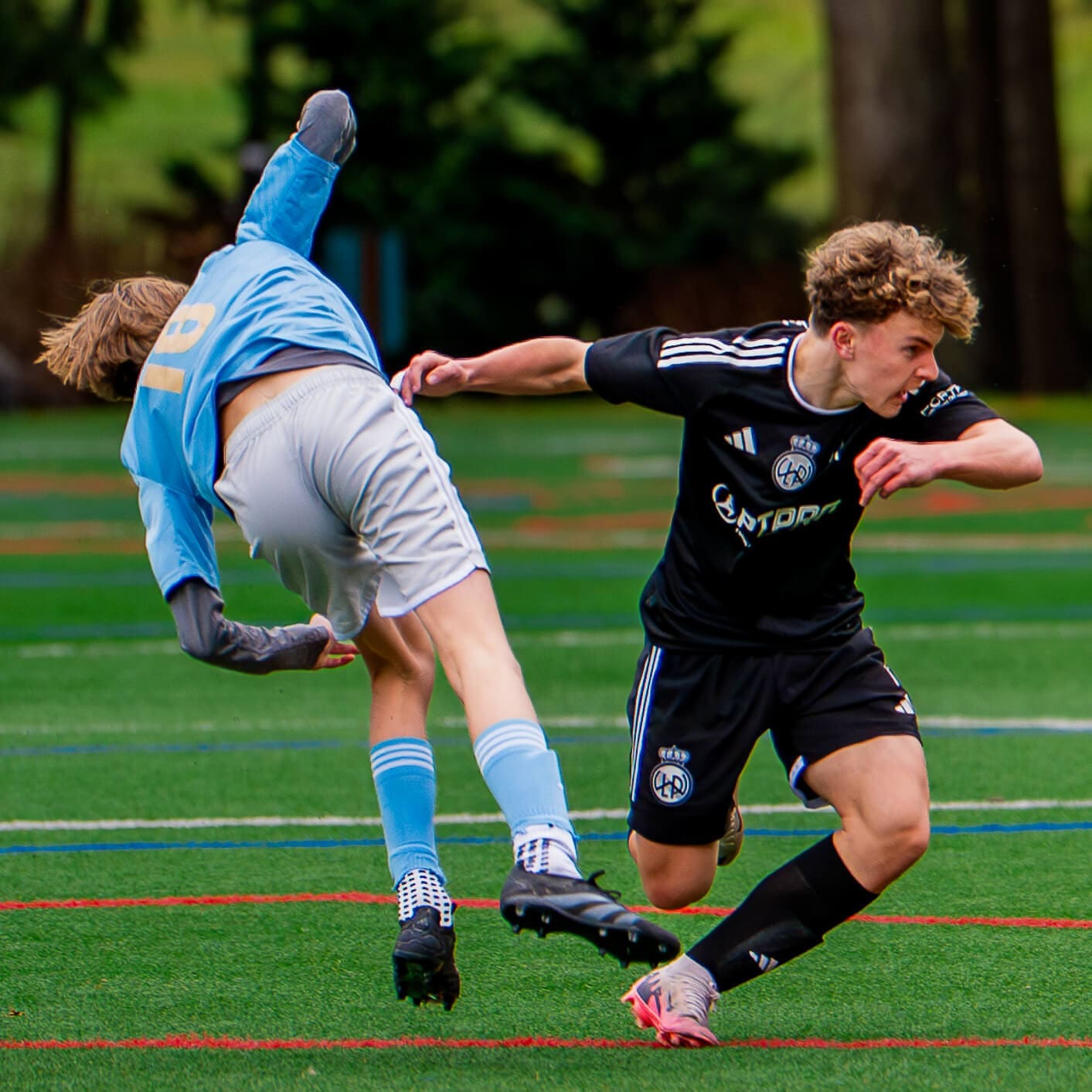 two youth soccer players, playing a game, caught mid action